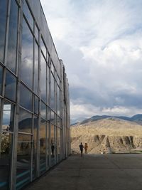 People on glass against sky