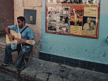 Full length of man sitting on wall