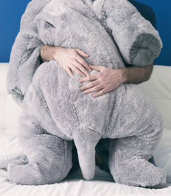 Midsection of man holding stuffed toy on bed at home