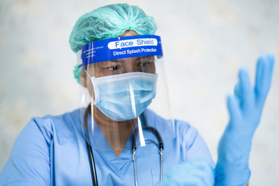 Close-up of doctor wearing mask and face shield standing at hospital