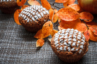 Chocolate muffins with apple filling on a background of autumn leaves and cinnamon