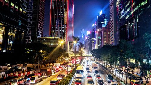 Traffic on city street amidst buildings at night