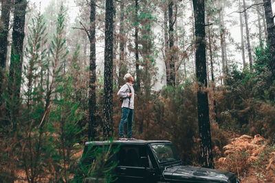 Man standing by car in forest