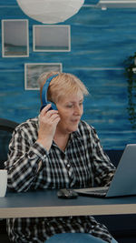 Senior woman wearing headphone using laptop