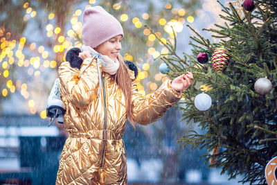 Rear view of woman standing by christmas tree