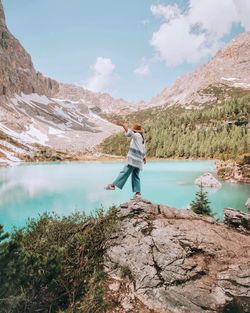 Full length of man standing on rock by lake against sky