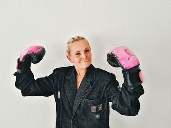 Portrait of mature woman wearing boxing gloves against white background