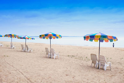 Deck chairs and parasols on beach against sky