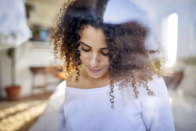 Close-up of thoughtful woman looking down at home seen through window