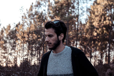 Portrait of young man standing against trees in forest