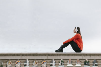Low angle view of woman standing against railing against sky