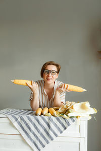 Portrait of young beautiful woman standing by table with corn 