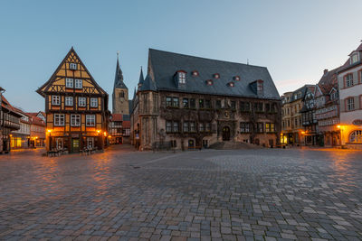 Street amidst buildings against sky at dusk