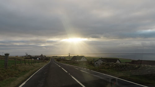 Road by landscape against sky during sunset