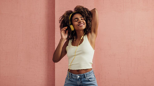 Portrait of young woman standing against wall