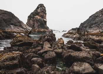 Rock formations by sea against clear sky