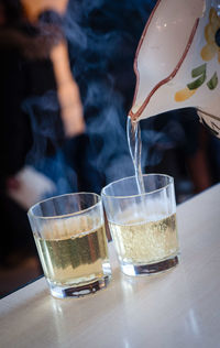 Pitcher pouring mulled wine in glass on table