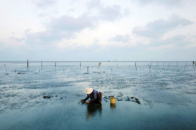 Person sitting on beach against sky