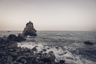 Scenic view of rocks in sea against clear sky