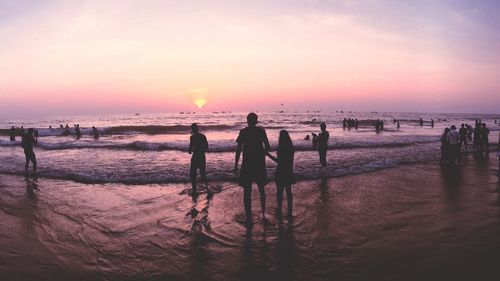 Silhouette people on beach against sky during sunset