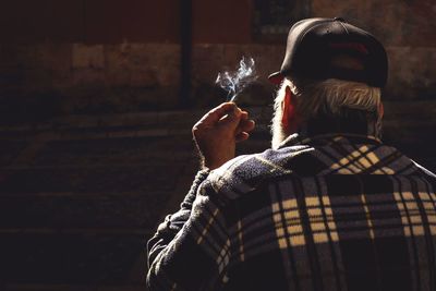 Rear view of man smoking cigarette outdoors