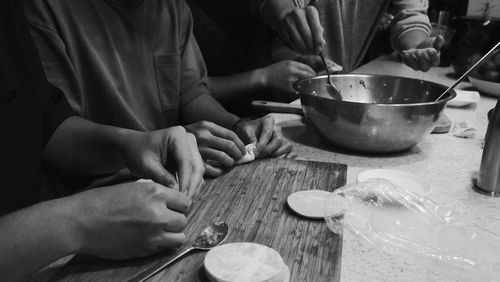 Midsection of people having food in kitchen