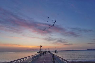 Pier over sea against sky during sunset