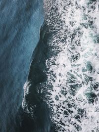 High angle view of sea waves splashing on rock