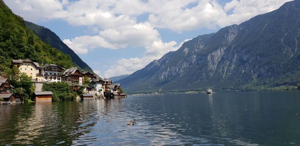 Scenic view of lake by buildings and mountains against sky