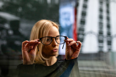 Close-up of woman wearing eyeglasses against buildings in city