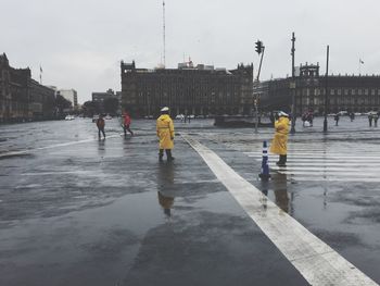 People on wet road during winter against sky
