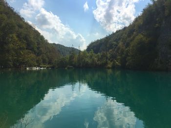 Scenic view of calm lake surrounded by trees against sky