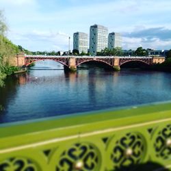 Bridge over river in city against sky