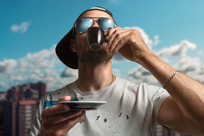 Portrait of man drinking coffee against sky