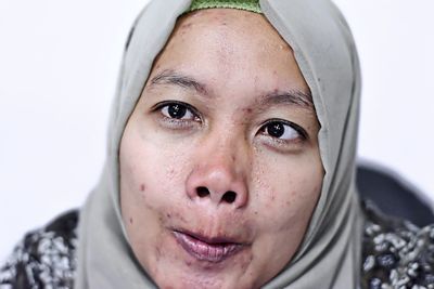 Woman wearing hijab making face against white background