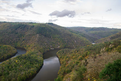 Scenic view of river by mountains against sky