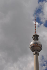 Low angle view of communications tower against cloudy sky