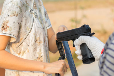 Cropped hand of criminal aiming gun towards woman 