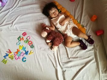 High angle view of baby sleeping by stuffed toy on bed at home