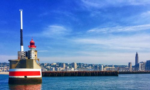 Lighthouse by sea against sky in city