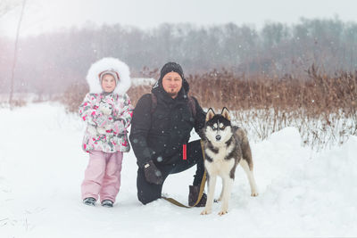 Portrait of man with dog on snow covered field