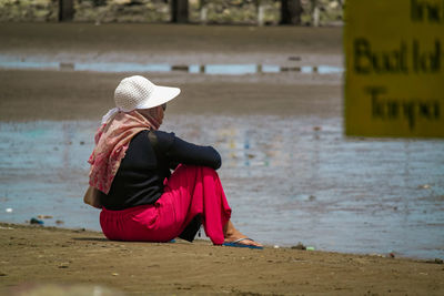 Side view of woman sitting at beach