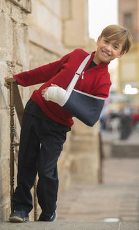 Portrait of smiling boy with orthopedic cast standing outdoors