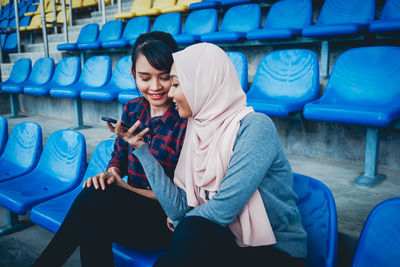 Woman using phone while sitting on laptop