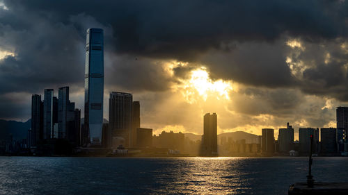 Modern buildings in city against sky during sunset