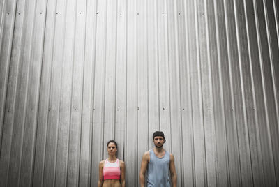 Low angle view of couple standing against metallic wall