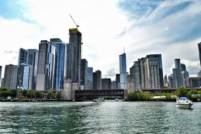 Modern buildings by river against sky in city