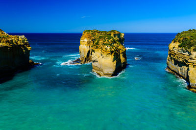 Scenic view of rocks in sea against blue sky