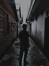 Rear view of man walking on footpath amidst buildings