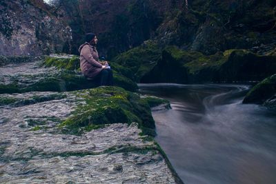 Man sitting on rock at river